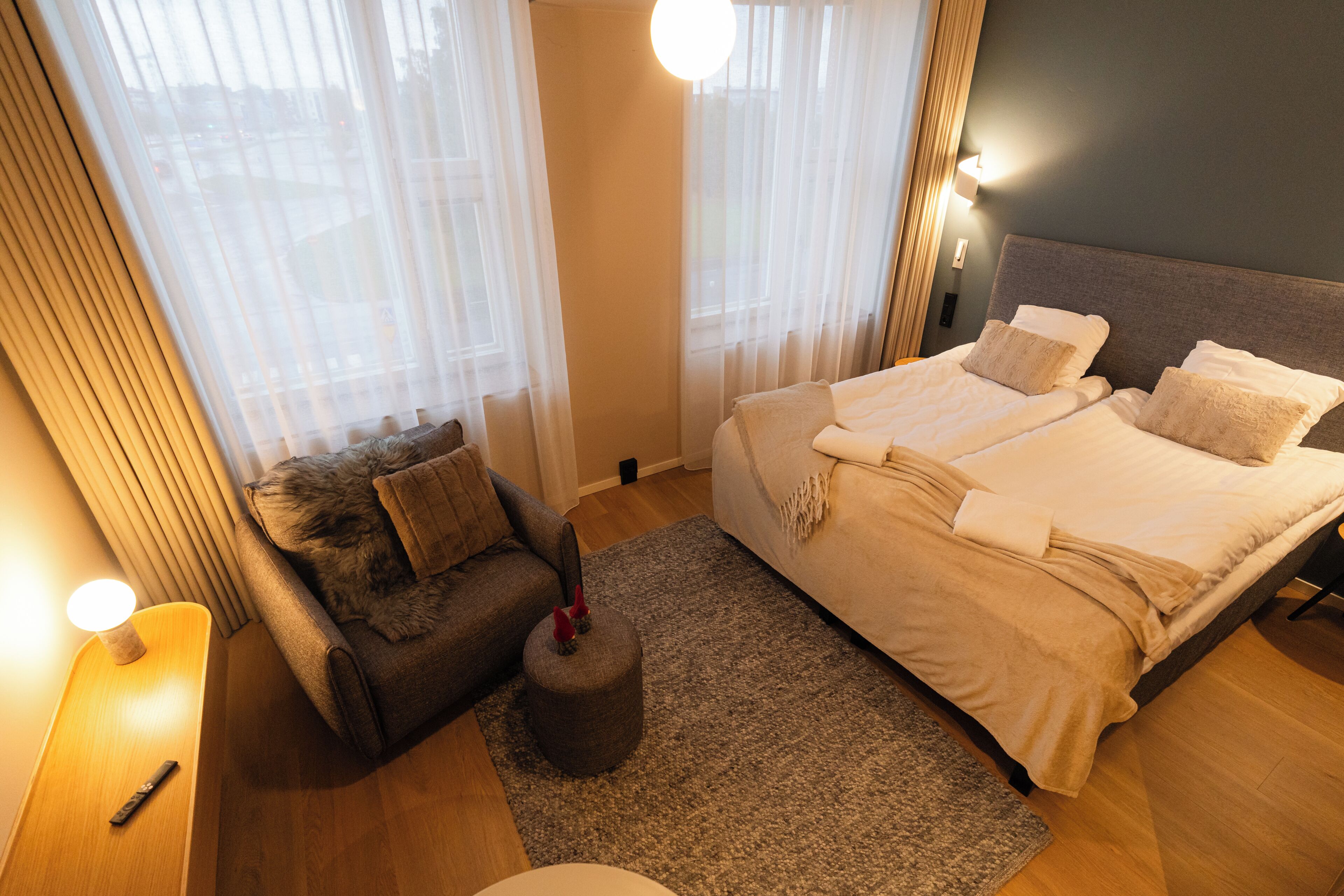 Una habitación de hotel con cama, sofá, alfombra y lámpara.