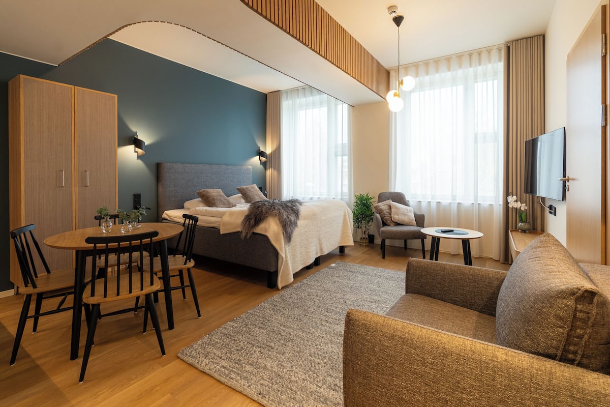 A modern living room with a bed, sofa, dining table, and chairs.