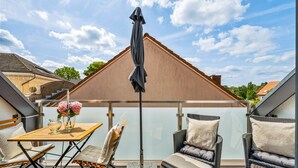 An outdoor patio area with a table, chairs, and an umbrella. - "Strandhafer" in Heiligenhafen - high-quality and ultra-modern temporary apartment (Heiligenhafen)