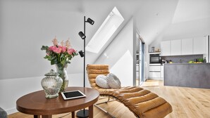 A modern living room with a sofa, a glass vase with flowers, a tablet, and a floor lamp. - "Strandhafer" in Heiligenhafen - high-quality and ultra-modern temporary apartment (Heiligenhafen)