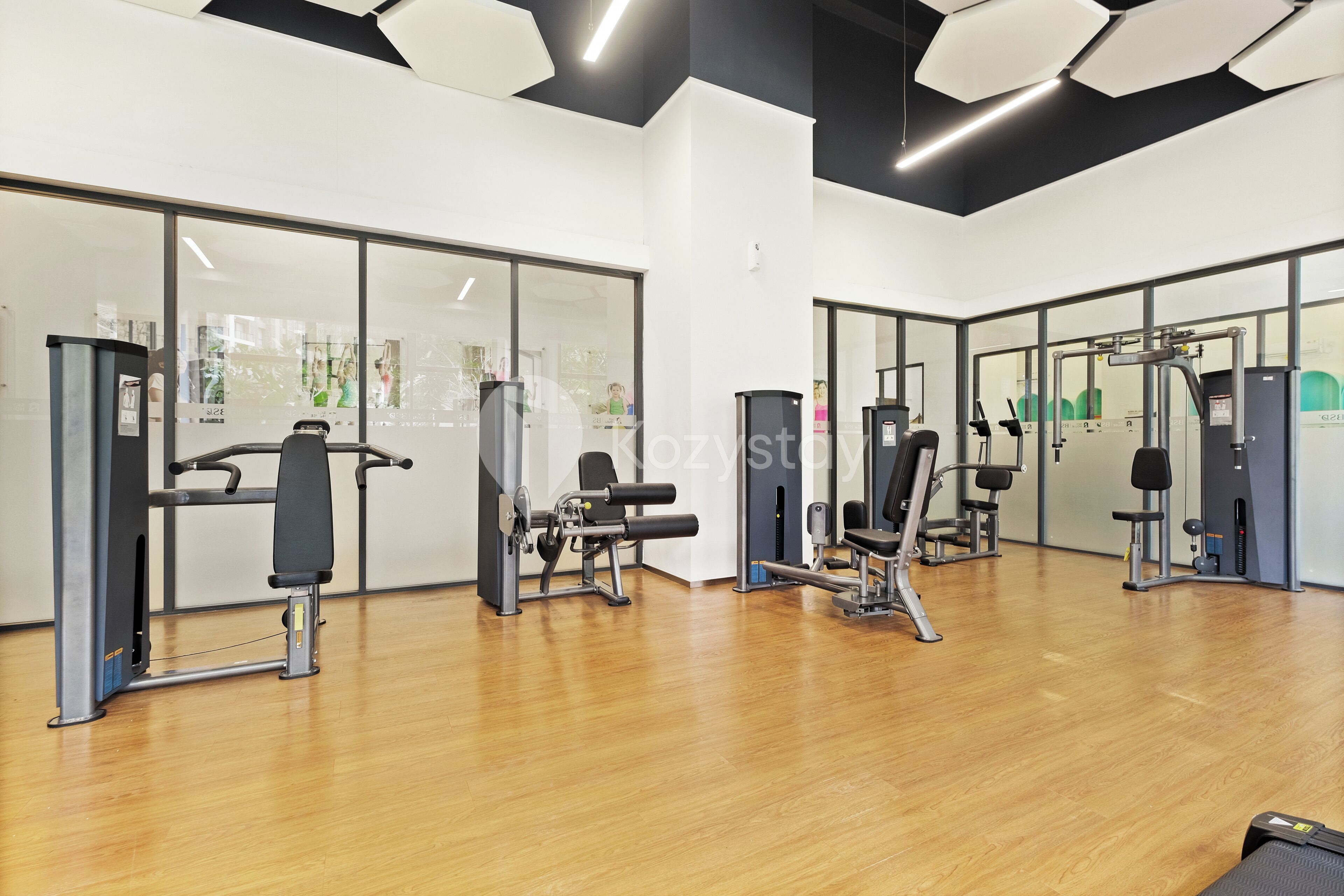 Une salle de sport équipée de matériel d’exercice, dotée de grandes fenêtres et d’un plancher en bois.