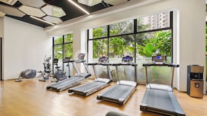 Une salle de sport équipée de tapis de course, de vélos elliptiques et d’un vélo d’appartement.