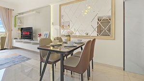 Un espace repas moderne avec une table en verre, des chaises rembourrées et un grand miroir.