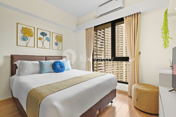A neatly made bed with a brown headboard, a beige throw blanket, and decorative pillows. - Solace by Kozystay - BSD (Pagedangan)