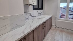 A kitchen with a marble countertop, wooden cabinets, a window with a view, and a built-in oven.