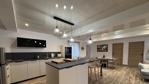 A modern kitchen with a central island, a dining area with a table and chairs, and a built-in oven. - Modern 3-ears cottage in Cognat-Lyonne, 6 ppl, charm and comfort (Cognat-Lyonne)