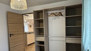 A bedroom with a bed, a wardrobe with multiple shelves, and a hanging light fixture. - Modern 3-ears cottage in Cognat-Lyonne, 6 ppl, charm and comfort (Cognat-Lyonne)