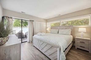 Quarto com cama, mesas de cabeceira e vista para o exterior.