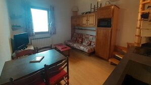 Une cuisine compacte avec des meubles de rangement en bois, une table à manger et un canapé.