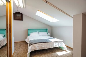 A bedroom with a bed, a skylight, and a wooden door. - Pine Acres Velo (Durango)