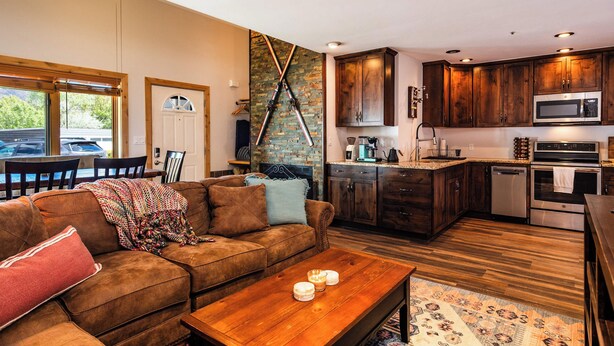 Eine moderne Küche mit dunklen Holzschränken, Edelstahlgeräten und einer Wand mit Ziegeloptik.