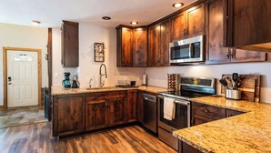 A kitchen with wooden cabinets, stainless steel appliances, and a granite countertop.