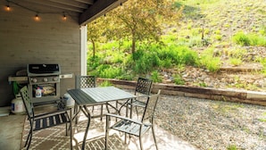 Eine Terrasse im Freien mit Grill, Tisch und Stühlen.