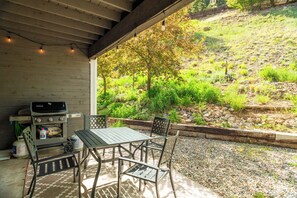 Un patio exterior con una parrilla, una mesa y sillas.