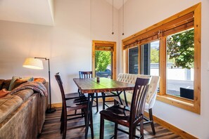 Un comedor con mesa y sillas de madera, un sofá y una lámpara.