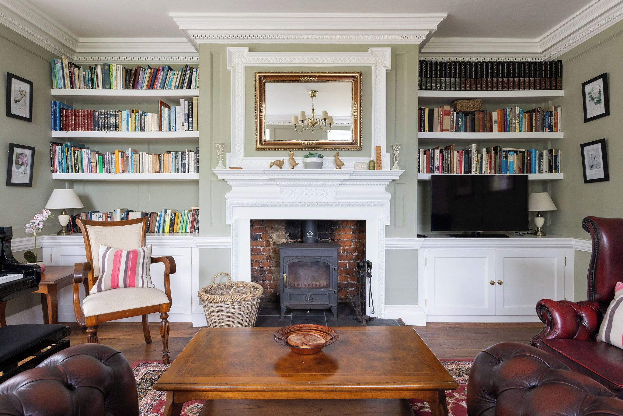A living room with a fireplace, bookshelves, a television, and leather furniture.