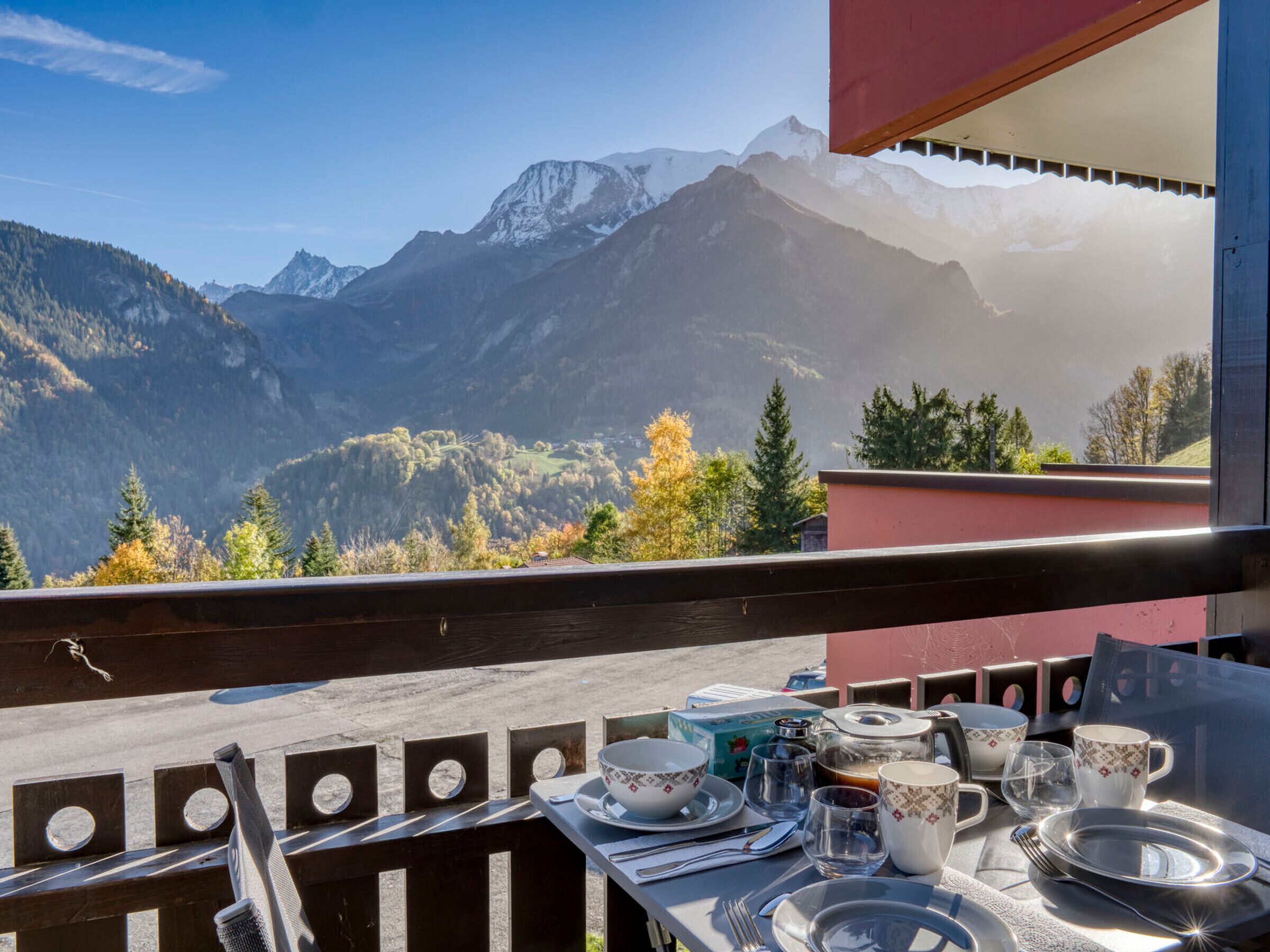 Ein Esstisch mit Tellern, Schüsseln, Gläsern und Besteck auf einem Balkon mit Blick auf die Berge.