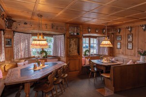Un interior de madera con una gran mesa de comedor, bancos e lámparas colgantes.