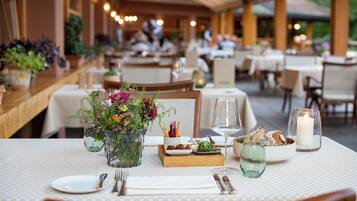 Ein Restaurant mit gedeckten Tischen, einer Blumenvase, einer Kerze und einem Weinglas.