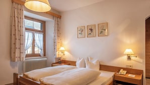 A hotel room with a double bed, two bedside tables with lamps, a window with curtains, and three framed botanical prints on the wall. - Gasthof Löwen by Hotel Montafoner Hof (Tschagguns)