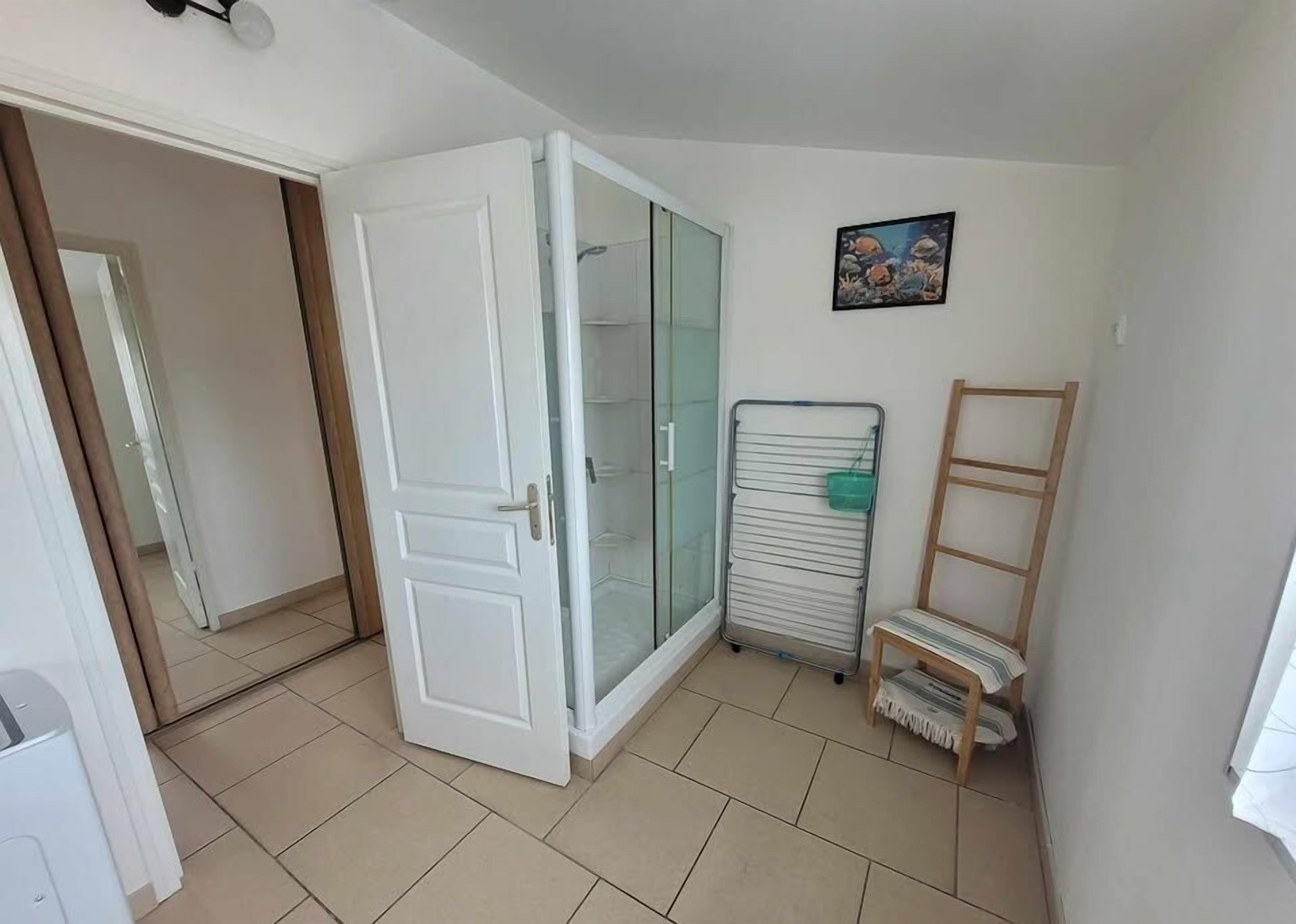 Ein Zimmer mit einer Schiebeglastür, einem Heizkörper, einer kleinen Holzleiter und einem gerahmten Bild an der Wand.