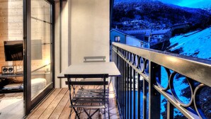 Un balcon avec une table et des chaises, un téléviseur et une vue sur un paysage enneigé.