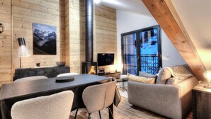 Un intérieur chaleureux avec un mur en bois, une cheminée, un canapé et un coin repas.