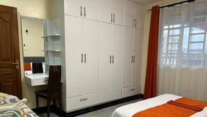 A hotel room with a bed, a desk, a wardrobe, and a bathroom.