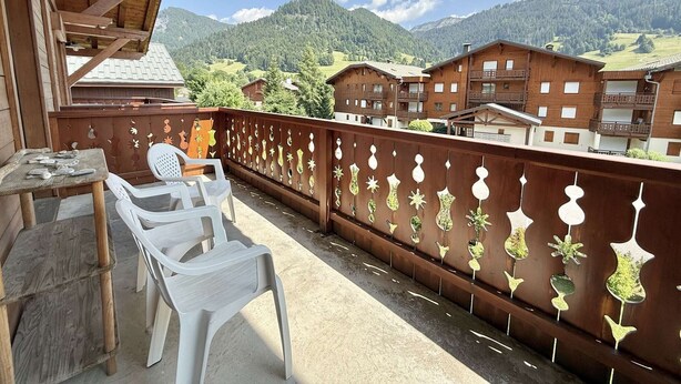 Ein Balkon mit Holzbalkon, einem Tisch und zwei Stühlen.
