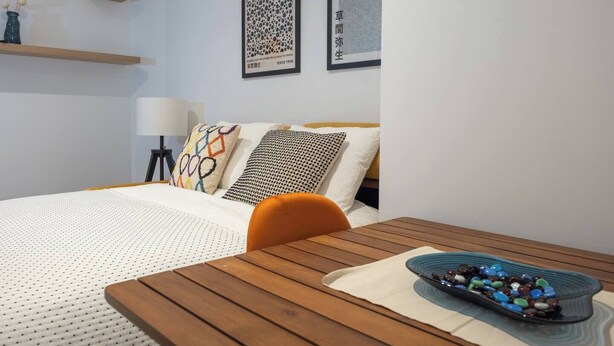 A modern hotel room with a wooden bed, a small table with a bowl of decorative stones, and two framed artworks on the wall. - Apartments EL Aljibe - Ap.1 (Badajoz)