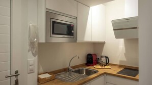 A compact kitchen with a microwave, coffee maker, and toaster on the countertop. - Apartments EL Aljibe - Ap.1 (Badajoz)