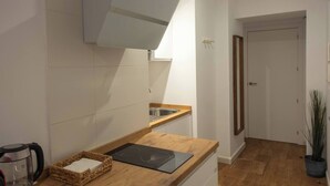 Una cocina moderna con azulejos blancos, encimera de madera, horno empotrado y una planta en maceta.