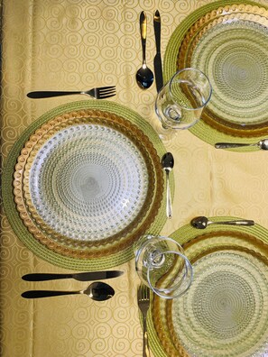 A table set with green and gold plates, silverware, and clear glassware. - The Penthouse Essentials (Douala)