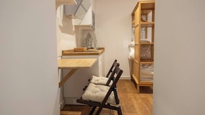 A narrow room with a wooden chair, a small wooden table, and a built-in bookshelf. - EL Aljibe Apartments - Ap.4 (Badajoz)