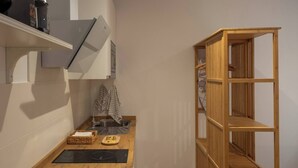 A compact kitchen with a wooden countertop, a built-in stove, a sink, and a wooden shelving unit. - EL Aljibe Apartments - Ap.4 (Badajoz)