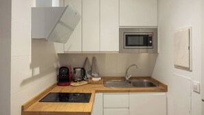 A compact kitchen with white cabinets, a microwave, a coffee maker, and a sink. - EL Aljibe Apartments - Ap.5 (Badajoz)