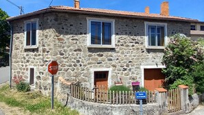Un bâtiment en pierre avec un panneau d’arrêt rouge, une clôture en bois et un panneau bleu indiquant la présence d’une chapelle.