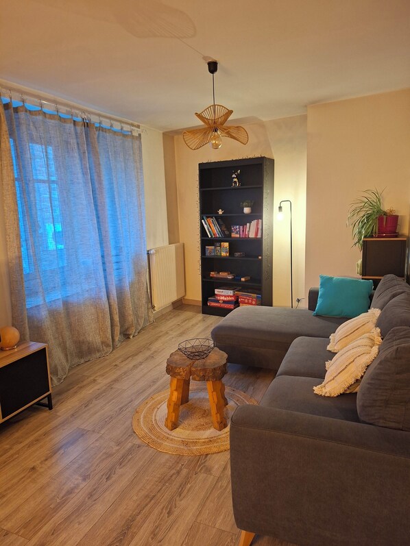 A living room with a sofa, a bookshelf, a floor lamp, and a radiator.