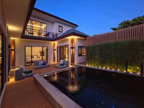 A modern house with a swimming pool, a balcony, and a well-lit interior. - Oasis Residences - Serene Sanur Sanctuary, Modern Comfort Meets Nature (Denpasar)