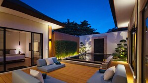 Ein moderner Außenbereich mit Holzdeck, grauen Sofas und einem kleinen Pool.