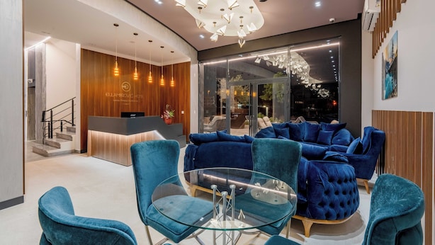 A modern hotel lobby with a reception desk, blue seating area, and a glass table. - Dulamerovic Hotel (Ulcinj)