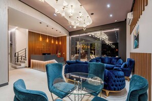 A modern hotel lobby with a reception desk, blue seating area, and a glass table. - Dulamerovic Hotel (Ulcinj)