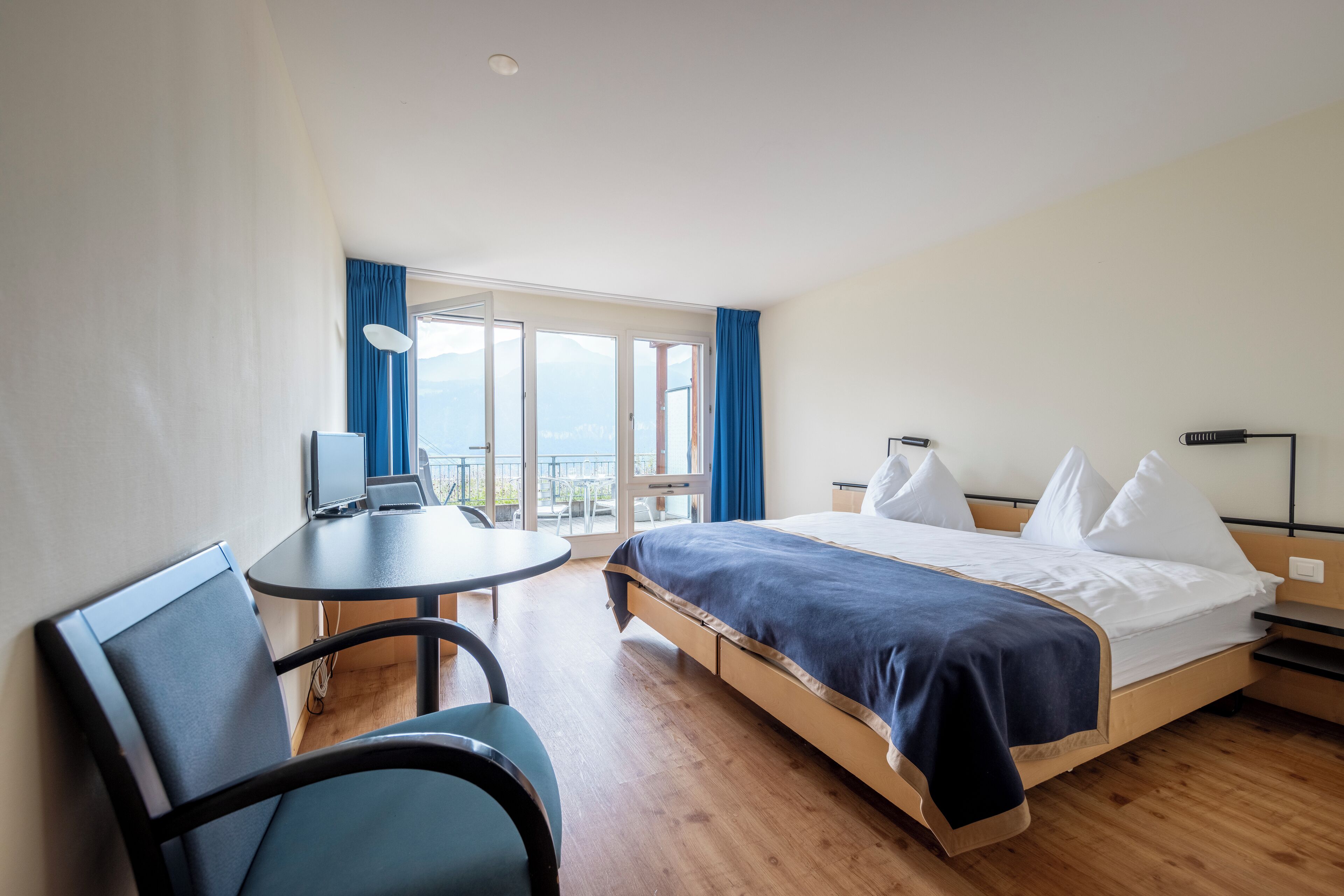 A hotel room with a bed, a desk, and a chair.