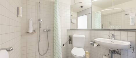 Baño con ducha, inodoro, lavamanos y espejo.