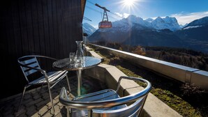 Una terraza con mesa y sillas, con vistas a un paisaje montañoso y un telesilla.