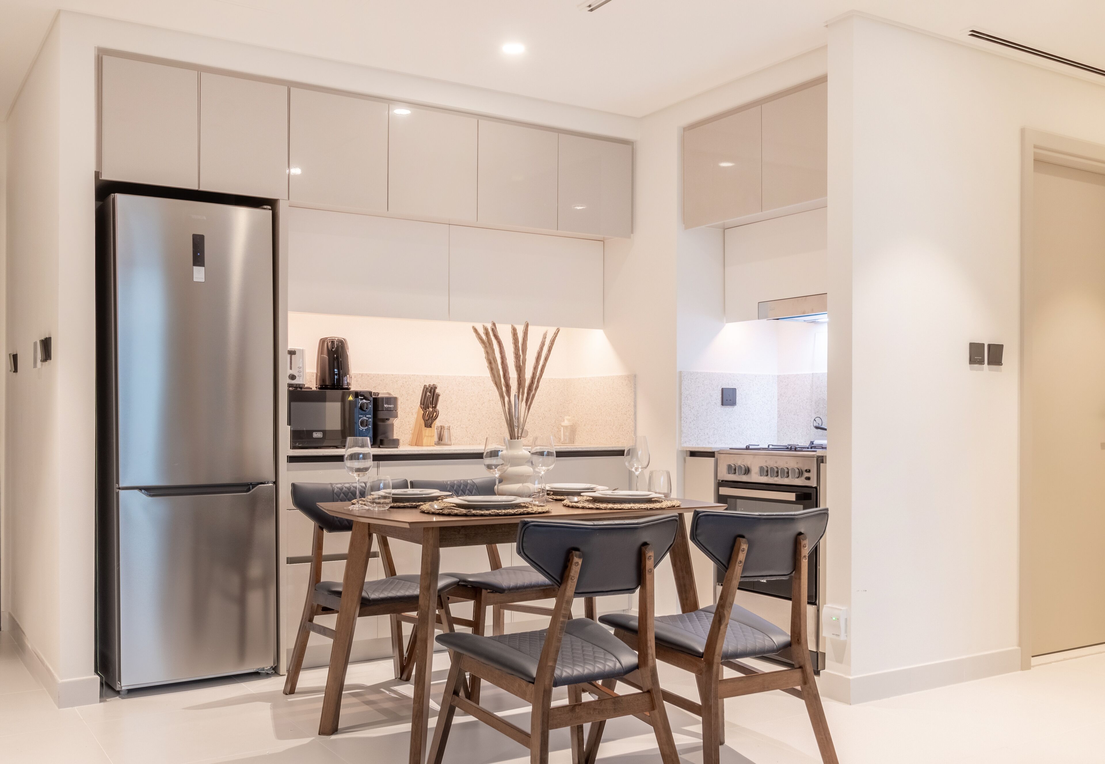 Una cocina moderna con nevera integrada, una mesa de comedor con sillas y una isla de cocina con microondas y cocina.