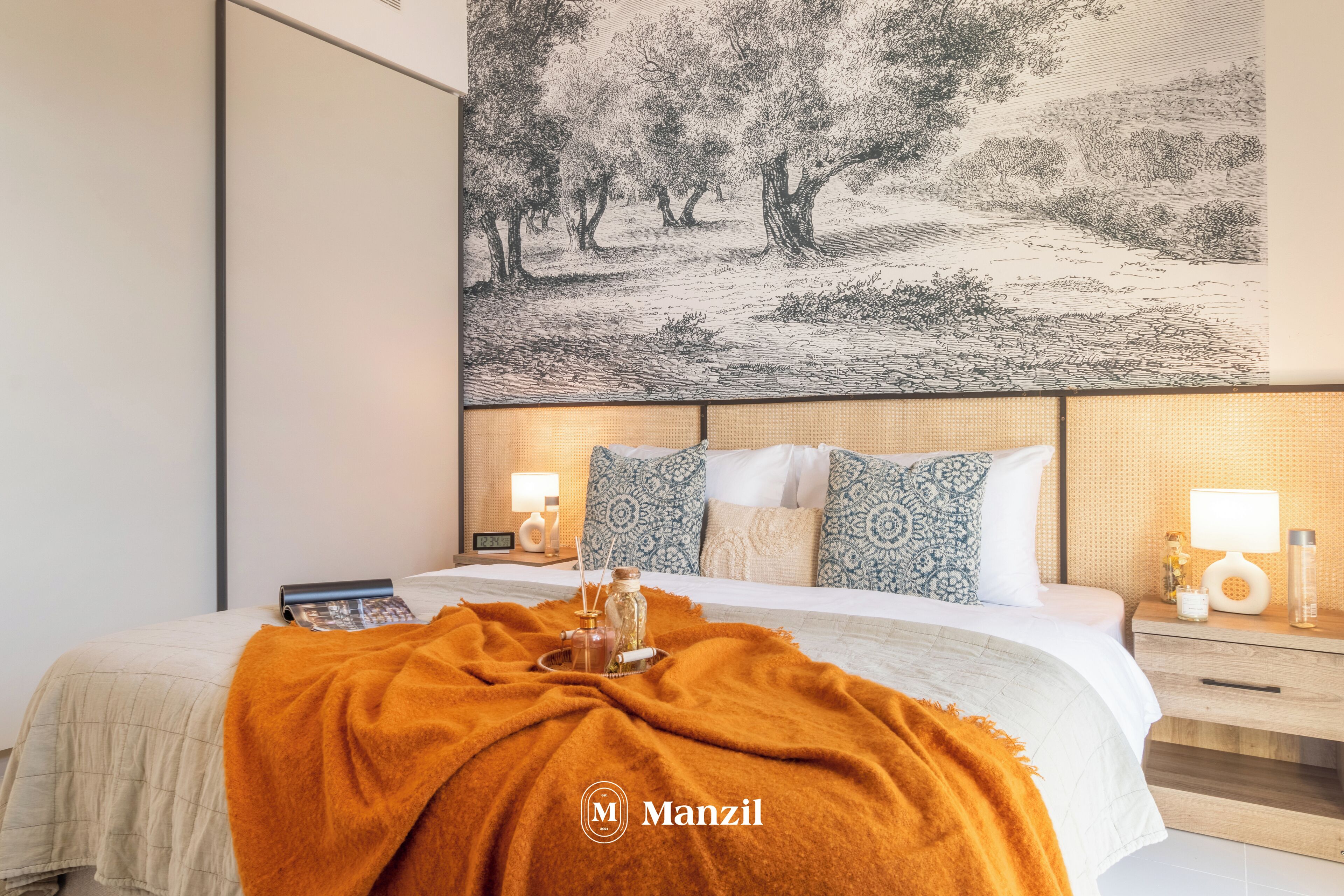 Ein Hotelzimmer mit einem großen Bett, einem Nachttisch mit Lampe und einem Baumgemälde an der Wand.