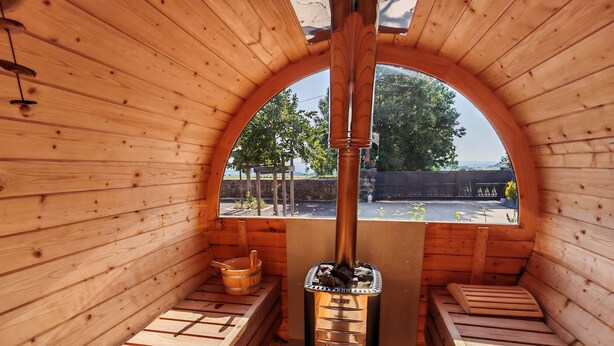 A sauna with wooden walls and benches, a central heating unit, and a view of the outdoors. - Whole house (Saint-Jean-Lachalm)