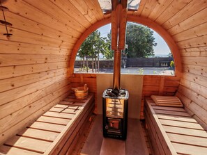 Eine Sauna mit Holzwänden und -bänken, einer Zentralheizung und Blick ins Freie.