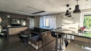 A modern living room with a sectional sofa, a flat-screen TV, and a dining area with a table and chairs. - Whole house (Saint-Jean-Lachalm)